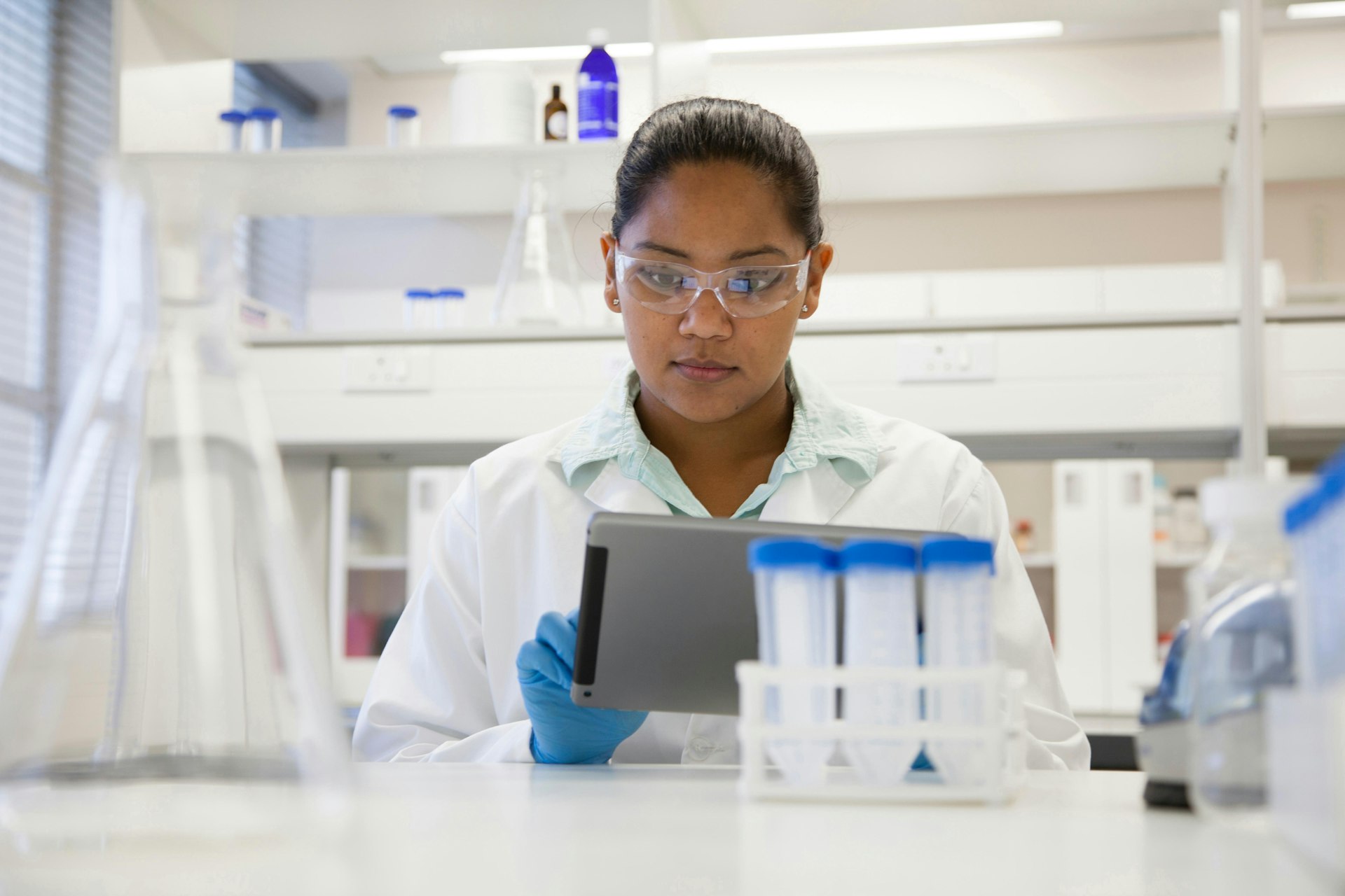 Woman scientist reading data from a tablet while in a lab.